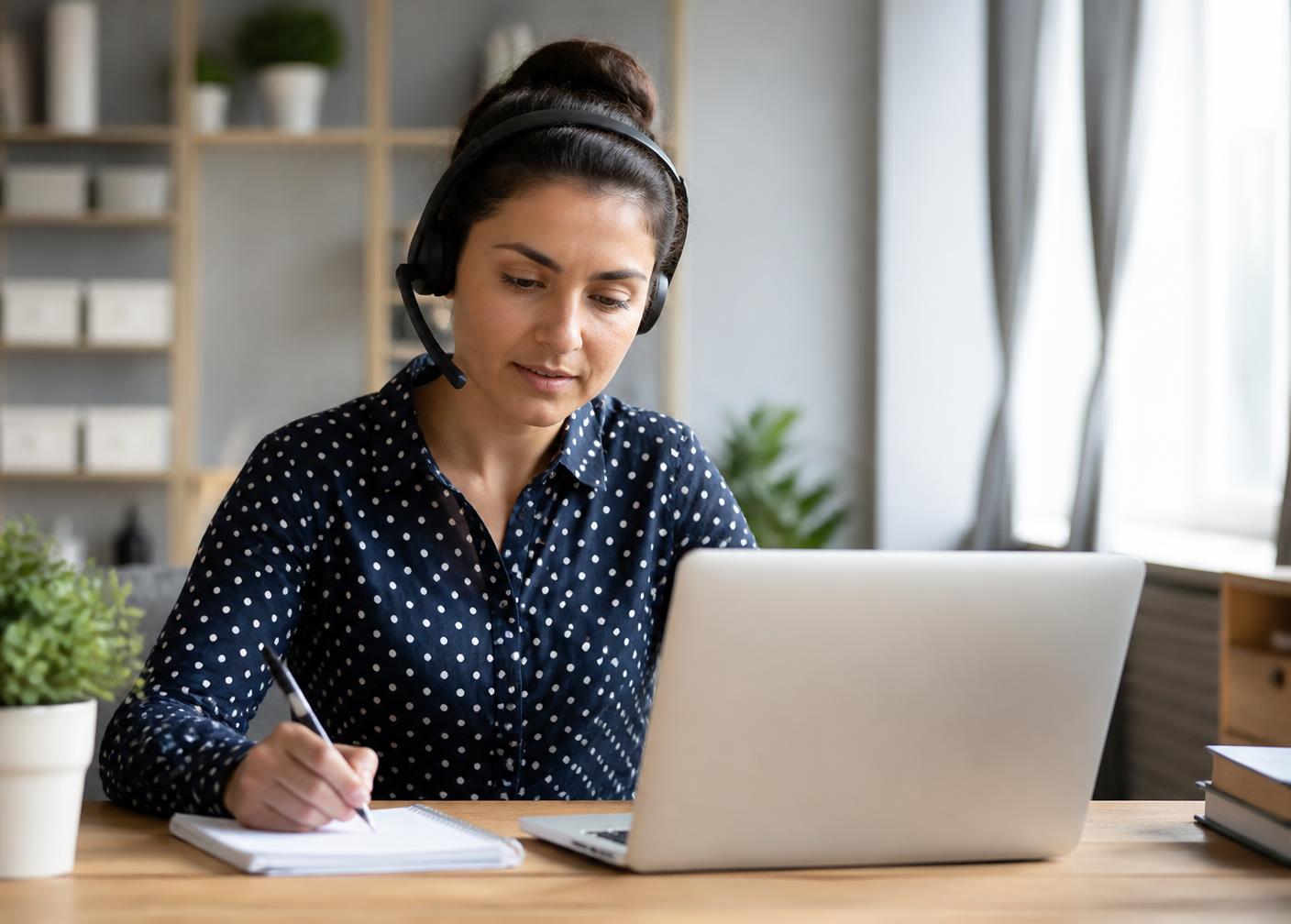 Remote customer service representative taking notes during a call at a home desk